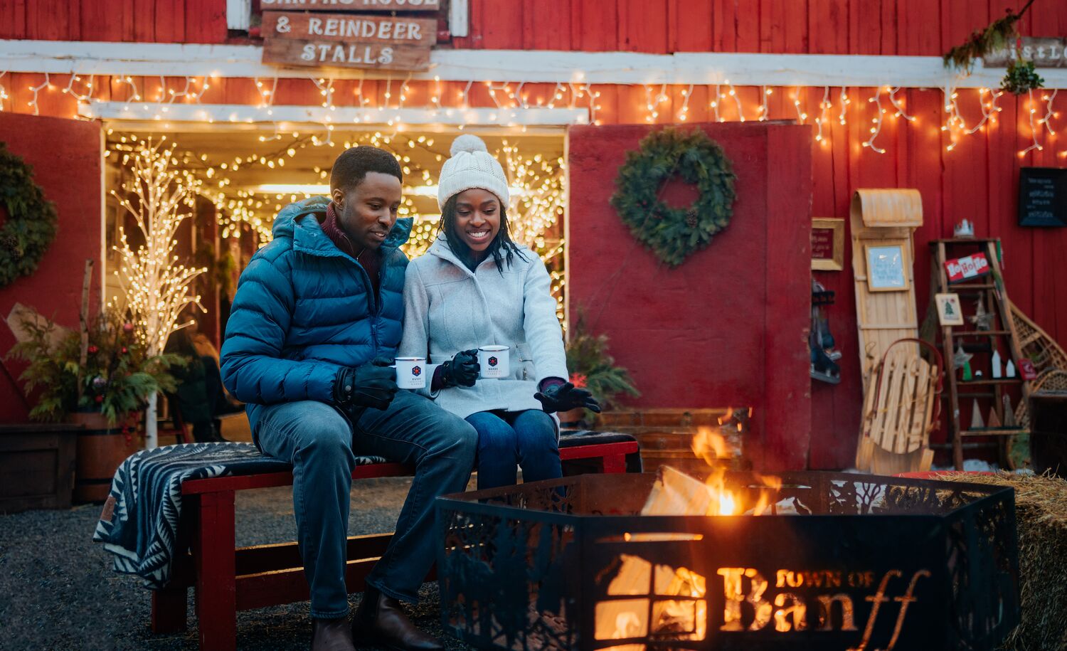 A couple sits at a campfire at the Banff Christmas Market.